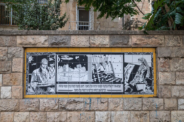 Jerusalem, Israel, 26 September 2026. Black and white mosaic tile mural by Ephraim Moses Lilien near historic Bezalel Academy  with Hebrew text and Jewish figures decorates a stone wall in city. © elenarostunova