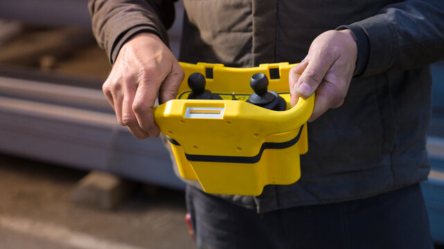 Close up of worker using an industrial crane remote control in a metalworking factory, illustrating heavy machinery, steel handling, manufacturing and industrial operations.