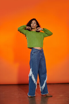 Fashionable young woman showcasing a vibrant look against an orange backdrop