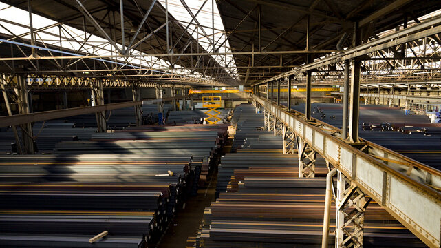 Industrial steel warehouse with overhead cranes and metal storage racks, showing large-scale manufacturing, heavy industry, material handling and industrial infrastructure.