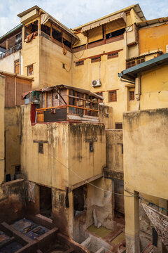 textured earthen walls, wooden structures, and traditional residential architecture overlooking the tannery complex in Fes, Morocco