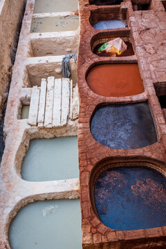 contrast between chalk-white treatment pits and dark liquid-filled stone vats at the historic Chouara Tanneries in Fes, Morocco