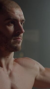 Focused athletic man with muscular torso and defined abs standing shirtless in soft indoor light, highlighting strength, discipline, and intense training dedication