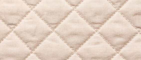 Fototapeta premium Quilted beige fabric texture with diamond stitch pattern. Padded cotton textile background for bedding and upholstery