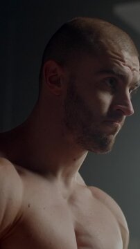 Focused muscular man in soft light showing determination, strength, and quiet concentration during an intense workout session in a minimalist indoor setting