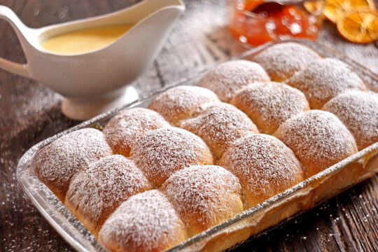 Traditional European Buchteln - sweet yeast buns with apricot jam and vanilla sauce on rustic wooden background.

Delicious homemade sweet yeast rolls (Buchteln, Buchty, or Buhtle) with apricot jam an