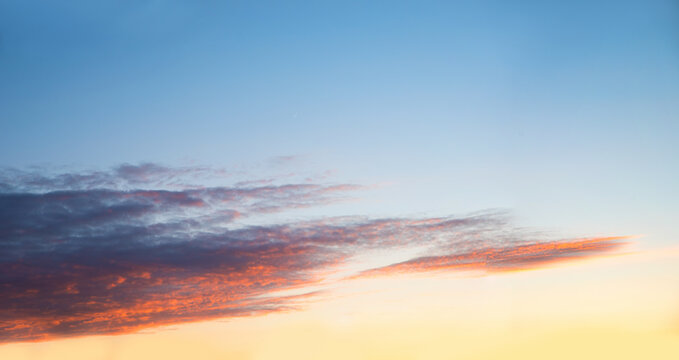 shiny evening sky, gradient from yellow to light blue. grey clouds  with red shine at sunset