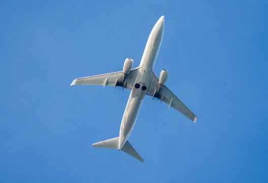 White unbranded commercial airplane flying in clear blue sky for mockup design