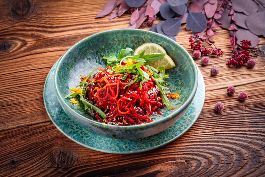 Vegetable vegan salad with red beet, carrots and green mix baby salad leaves served as close-up in a design bowl