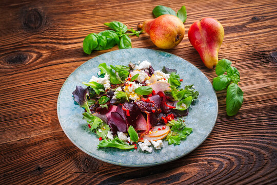 Vegetarian vegetable and fruit salad with red beets, pear, greens and feta sheep milk cheese served as close-up on a design plate