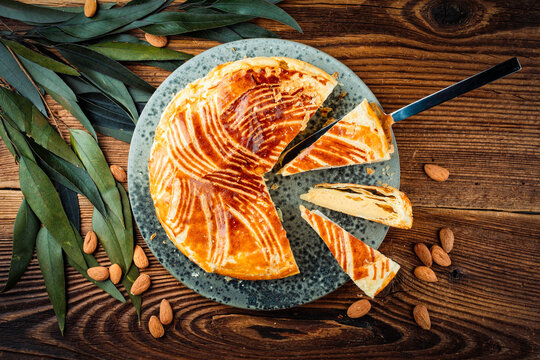 Classic traditional artisan homemade french galette des rois with almond cream fangipani filling - three kings cake served as top view on a design plate on wooden board