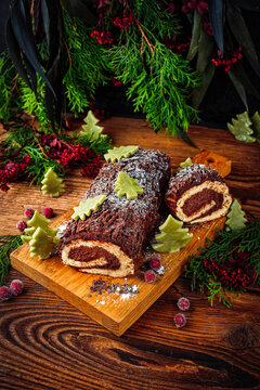 Traditional French homemade Christmas cake b&ucirc;che de no&euml;l, yule log with sponge cake and chocolate buttercream ganache served as close-up on a rustic wooden board