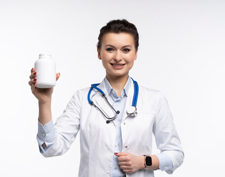 Attractive woman qualified specialist therapist wear white doctor robe hand hold pills isolated on white background.