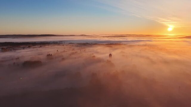 Flying above clouds and a city to show the shadows of a high rise building or a skyscraper in mist or fog during morning sunrise