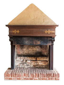 Antique medieval-style fireplace featuring weathered brick hearth, dark wooden lintel decorated with ornate brass hinges, and textured plaster pyramidal chimney hood, isolated on white clipping path