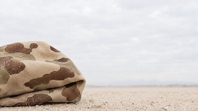 Desert camo fabric folded on sand texture  
