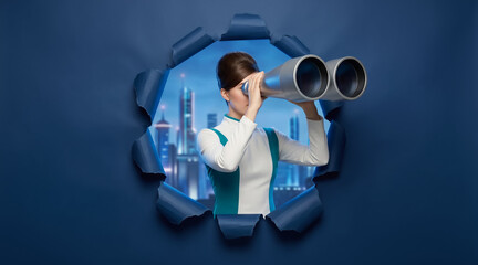 Fototapeta premium Woman looking through binoculars via a hole in blue paper, night cityscape visible behind, concept of vision and discovery. Business, exploration, future planning.