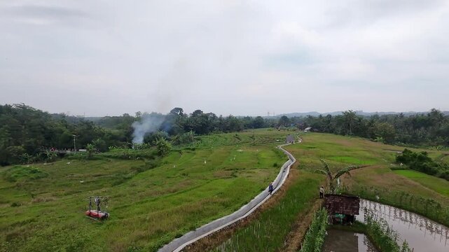 Drone shot of peaceful countryside road and paddy fields in Java