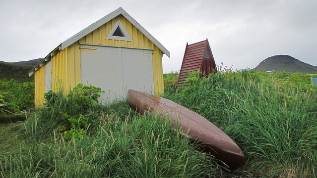 Yellow wooden shed and red canoe in tall grass in Iceland