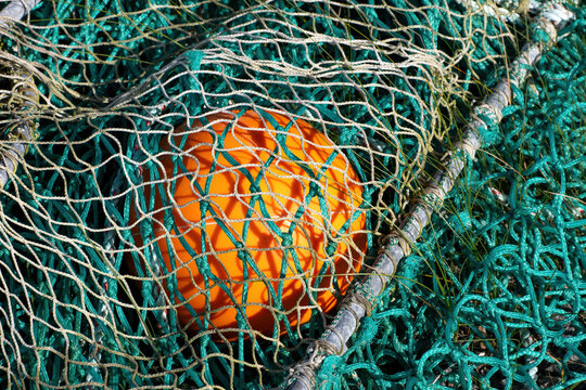 Orange fishing float tangled in green fishing nets