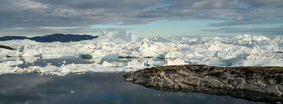 Climate Change conceptual photo. Global warming - Greenland Iceberg landscape of Ilulissat icefjord with giant icebergs. Icebergs from melting glacier. Arctic nature heavily affected by climate change