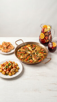 Rabbit and seafood paella accompanied by Patatas Bravas, tomato and herb bruschettas, and a pitcher of sangria with fresh fruit - PAELLA A LA VALENCIANA