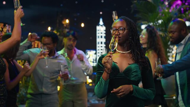 Portrait of a woman raising a champagne glass for a New Year's Eve toast as friends around her lift sparkling wine flutes during the celebration.