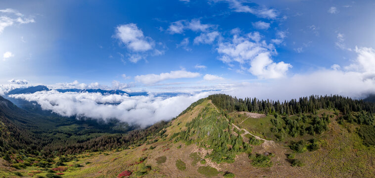 Panoramic Mountain View Above Clouds Over Chilliwack BC Canada With Forested Ridge And Blue Sky