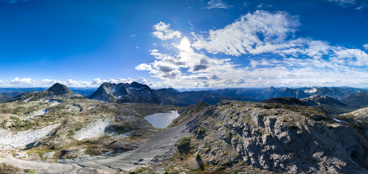Panoramic Alpine Mountain Range With Tarn Lake and Rocky Ridge Under Blue Sky in BC, Canada
