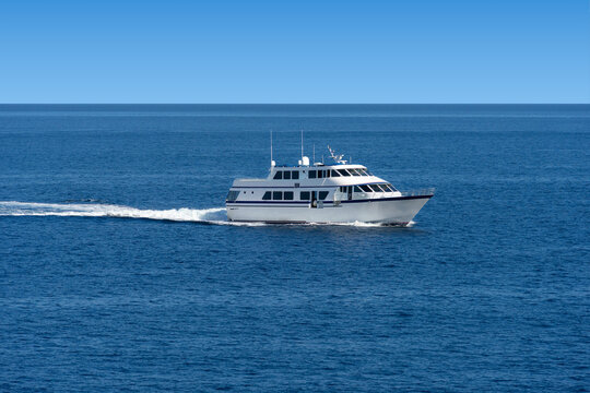On the open ocean water travels a white passenger ship with windows