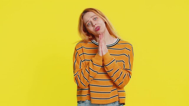 Please, God help. Caucasian woman in blouse praying, looking at camera and making wish, asking with hopeful imploring expression, begging apology, meditation. Adult girl isolated on yellow background