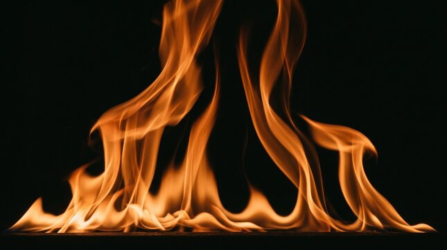 Bright orange fire flames dancing dynamically across completely dark black studio background