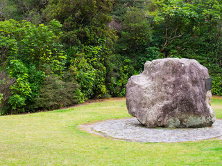 Large memorial boulder in a lush green park landscape © mcgimpseymike