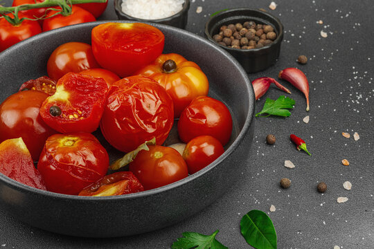 Lacto-fermented probiotic tomatoes in a bowl with garlic and spices, with fresh vine tomatoes