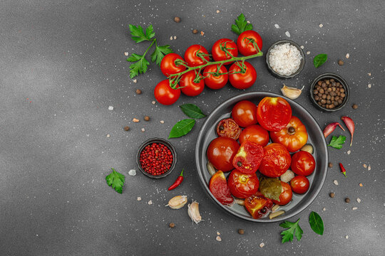 Lacto-fermented probiotic tomatoes in a bowl with garlic and spices, with fresh vine tomatoes