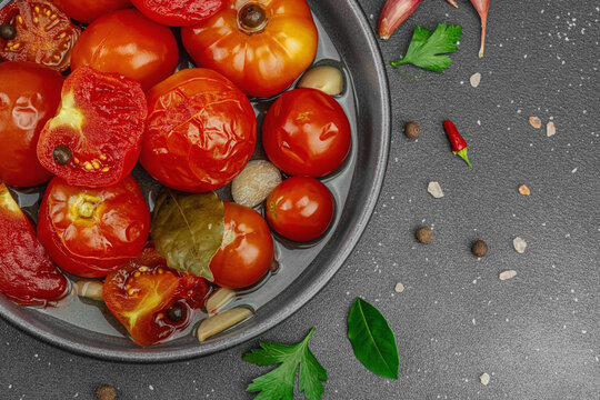 Lacto-fermented probiotic tomatoes in a bowl with garlic and spices, with fresh vine tomatoes