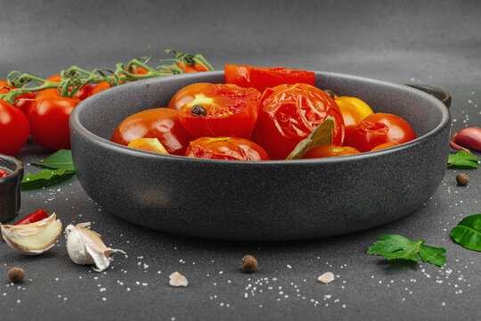 Lacto-fermented probiotic tomatoes in a bowl with garlic and spices, with fresh vine tomatoes