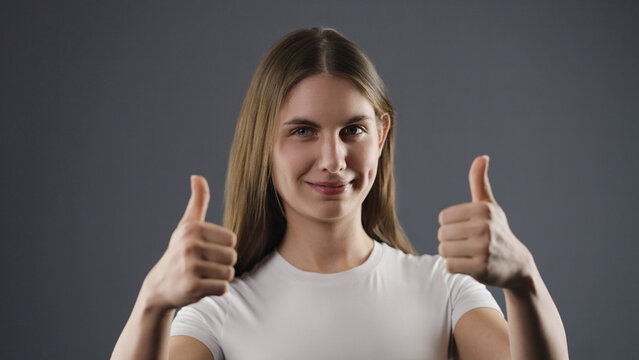 Young woman smiling while giving a positive double thumbs up gesture