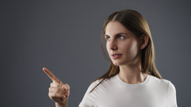 Young woman pointing and looking away, expressing curiosity or discovery