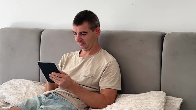 Man Reading Ebook on Digital Reader While Sitting at Home