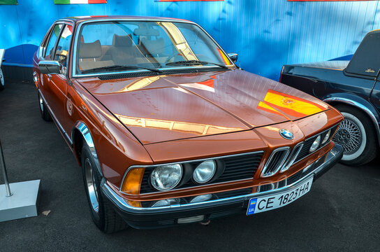 Classic metallic copper BMW 728 (E23) sedan featuring a signature sharknose front fascia, quad round headlights, and kidney grille, defining 1970s luxury