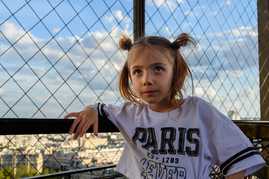 Little girl leans against railing, eyes wide with wonder