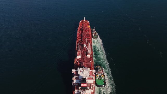 Large fuel tanker approaching Halifax Harbour, Nova Scotia, Canada, seen from a drone with two tugboats escorting the vessel through the entrance to the busy commercial port.