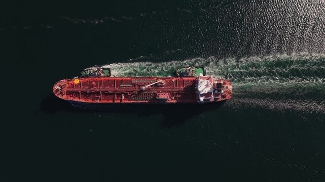 Aerial harbor view of a large petroleum tanker entering Halifax, Nova Scotia, Canada, with two tugboats providing assistance as the ship approaches the port terminal.