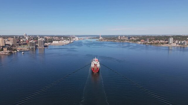 Drone footage of a large container ship approaching Halifax Harbour, Nova Scotia, Canada, with colorful intermodal containers stacked across the vessel as it sails toward the port.