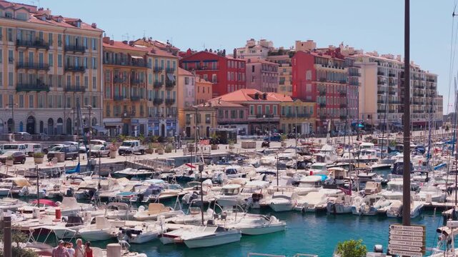 Telephoto slow drift over moored motorboats in Port Lympia marina toward colorful ochre and red quay facades, Nice, French Riviera, Cote d Azur, France