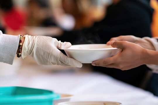 Charity volunteer serving warm food to help a person in poverty with community outreach support