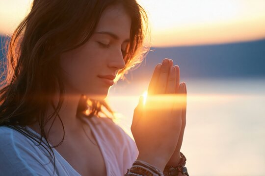 Woman in prayer by the ocean at sunset finding peace and serenity with hope and deep gratitude