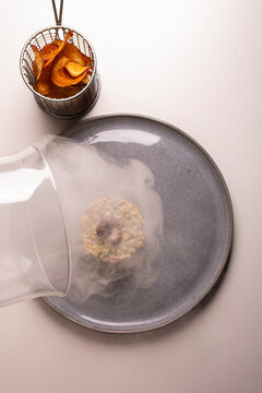 Smoked seafood tartare dish garnished with an octopus tentacle (finger food)