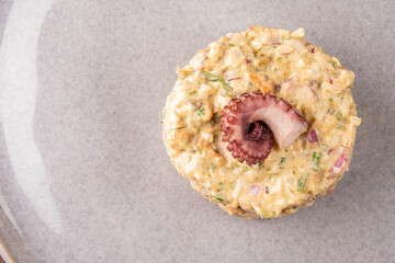Close-up of a succulent seafood tartare garnished with an octopus tentacle, top-down view. © mario